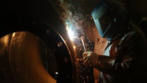 Welding cobot working alongside a technician on a metal assembly in a Michigan fabrication shop